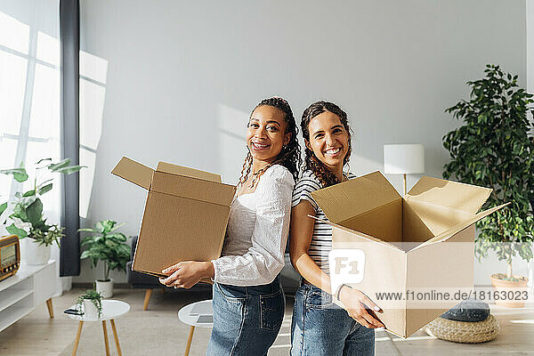 Smiling roommates with cardboard boxes in living room
