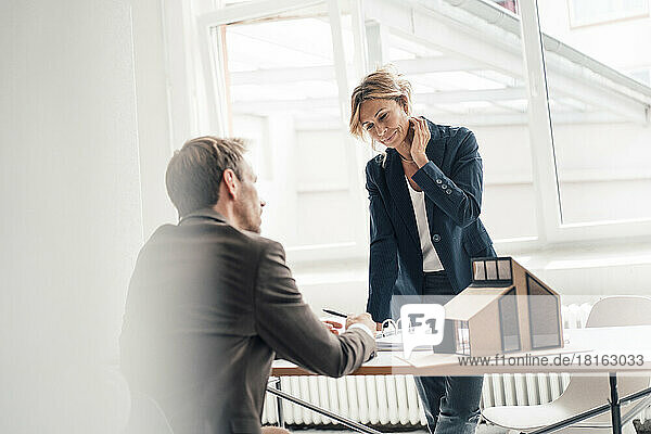 Businesswoman doing paperwork with customer at office