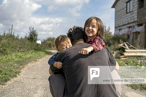 Father hugging happy sons on sunny day