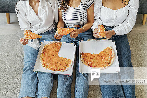 Mitbewohner sitzen zusammen zu Hause und essen Pizza