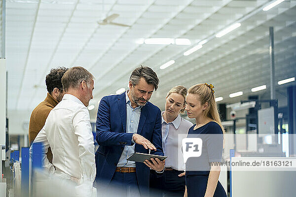 Businessman discussing over tablet computer with colleagues at warehouse