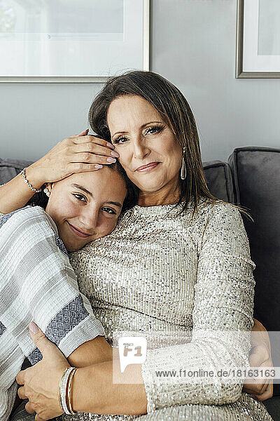 Smiling mature woman embracing daughter at home