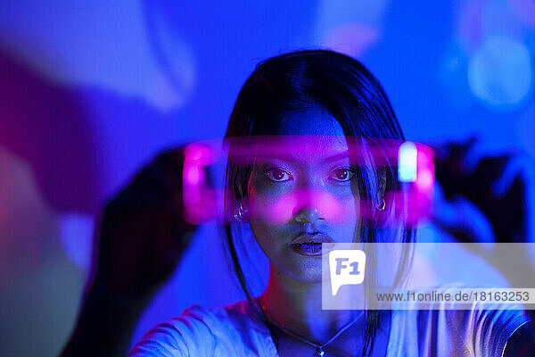 Junge Frau blickt durch eine futuristische LED-Brille