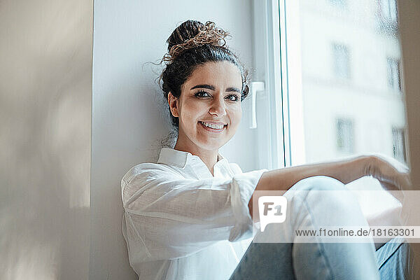 Smiling businesswoman sitting by window at work place