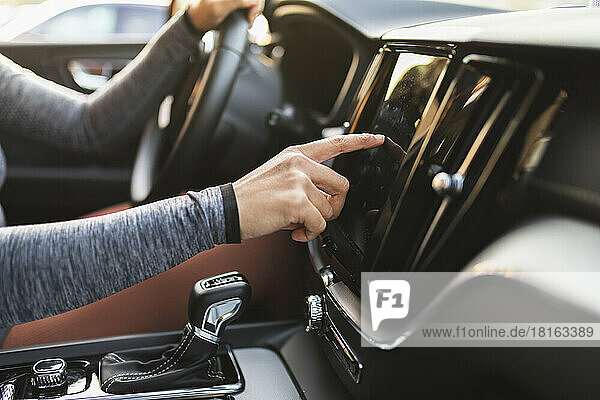 Die Hand einer Frau überprüft den Navigator  der im Auto sitzt