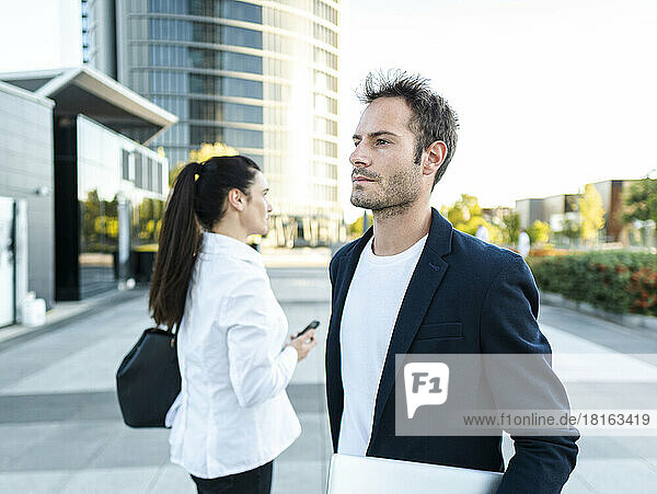 Thoughtful businessman standing by colleague at office park