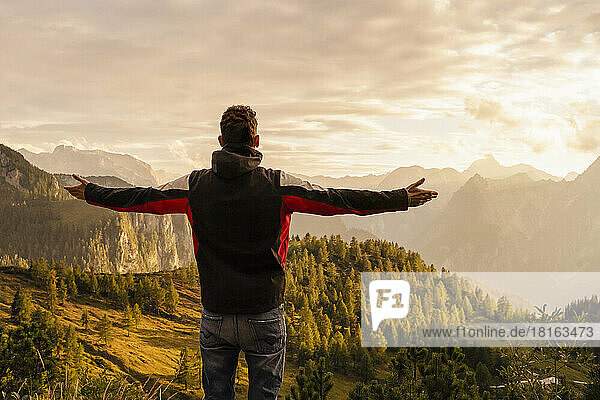 Man standing with arms outstretched on mountain