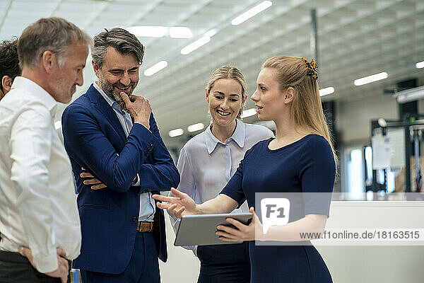 Blond businesswoman with colleagues discussing over tablet PC