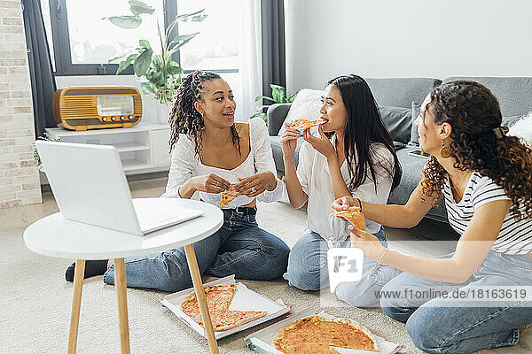 Friends eating pizza enjoying together in living room