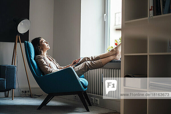 Businesswoman relaxing on chair at home