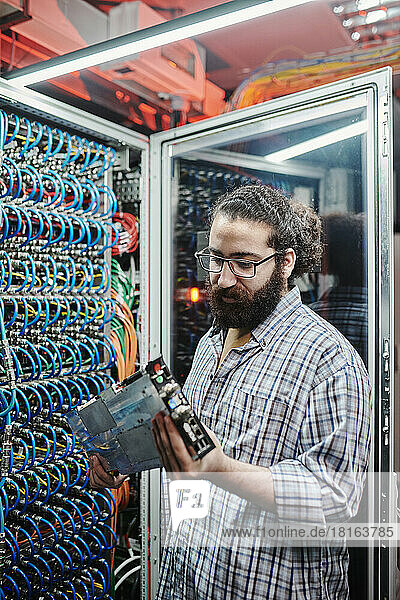 IT technician examining machine part in data center