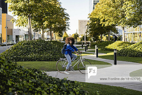 Smiling woman with bicycle on footpath at park