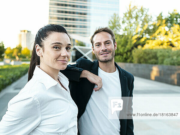 Smiling businesswoman with colleague standing at office park