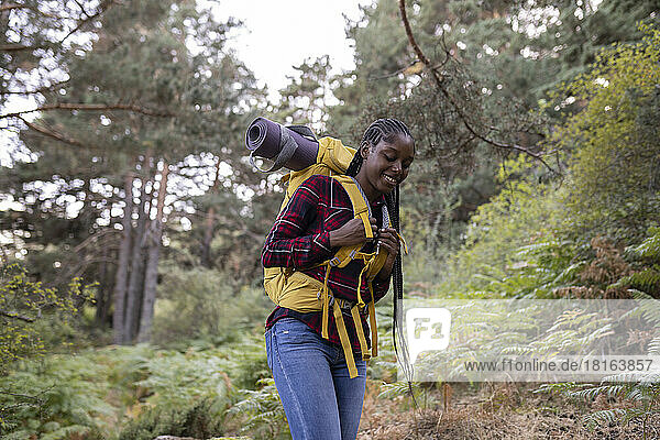 Glückliche Frau mit Rucksack spaziert im Wald
