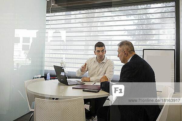 Businessman with colleague discussing at desk in office