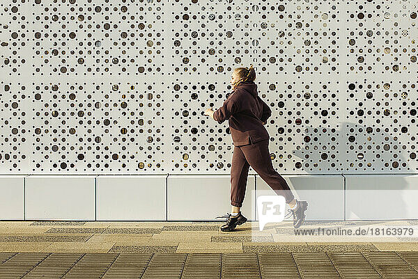 Plus size woman jogging by wall