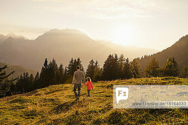 Father holding daughter's hand walking on grass
