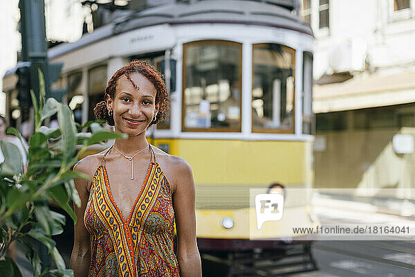 Smiling young woman standing in front of cable car