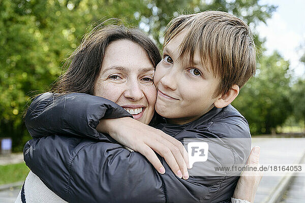 Smiling mother and son embracing in park