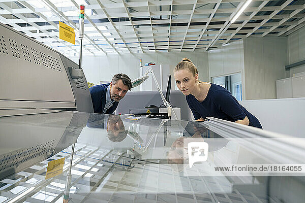 Young businesswoman with businessman examining 3D printing machine