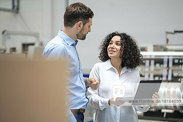 Businesswoman holding tablet PC discussing with colleague