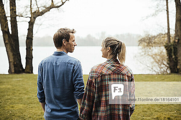 Smiling couple looking at each other standing in front of lake