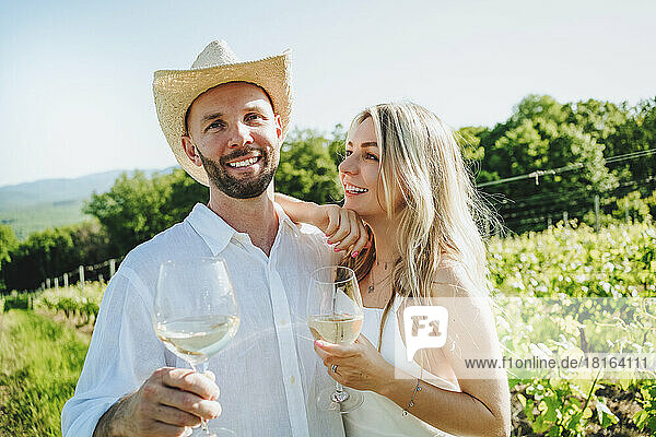 Happy couple with wine standing together at winery