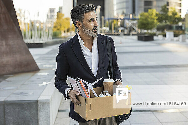 Fired businessman holding office supplies in box