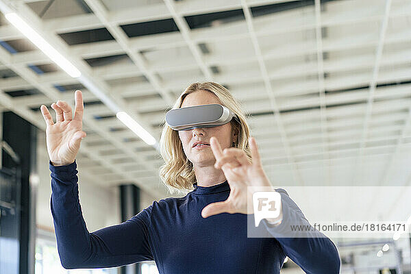 Blond businesswoman gesturing by wearing virtual reality simulator