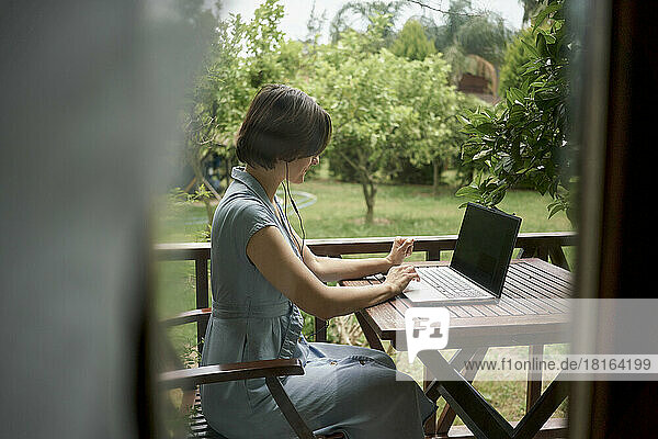 Freelancer using laptop sitting on balcony