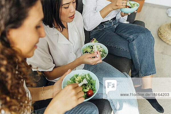 Multiracial roommates having salad for lunch at home