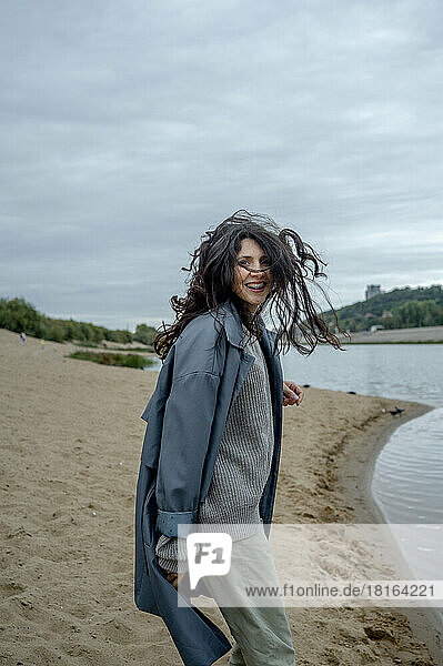 Playful woman wearing raincoat at shore