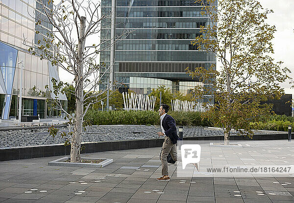 Geschäftsmann läuft auf Fußweg vor Bürogebäude