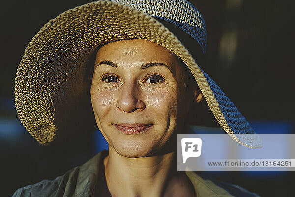 Smiling woman wearing hat with sunlight on face