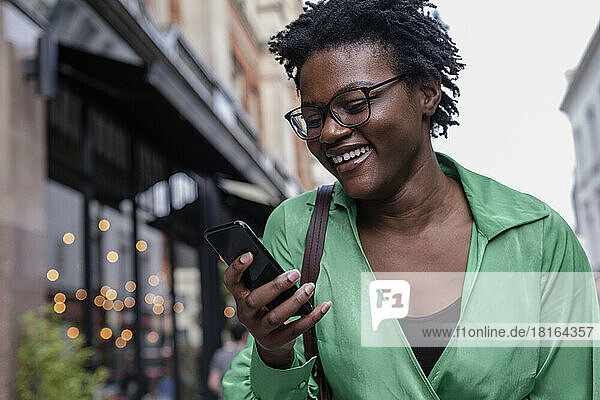 Happy young woman using smart phone in city