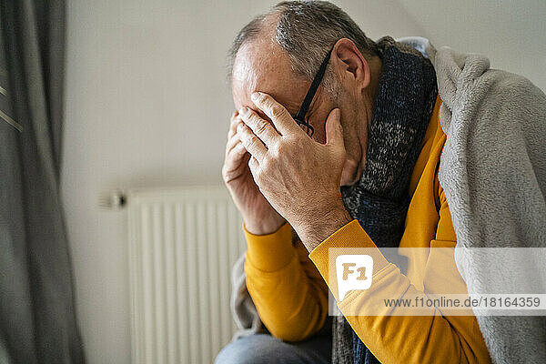 Depressed senior man covering face at home