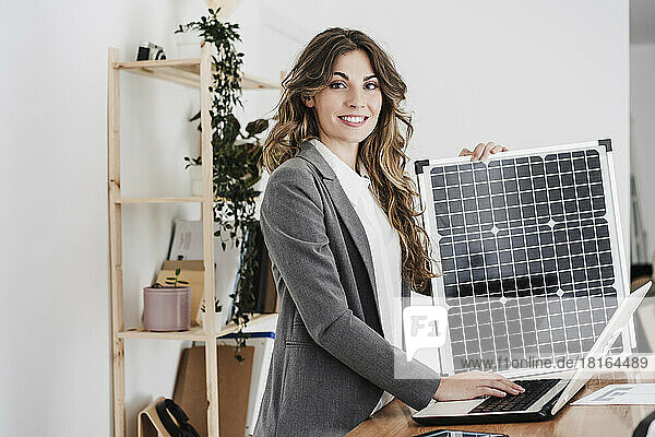 Modern businesswoman working on laptop using portable solar module in office