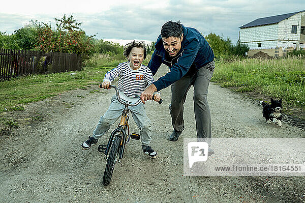 Happy father teaching son to ride bicycle