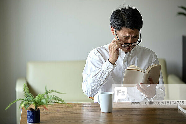 Japanischer Mann mit Alterssichtigkeit liest ein Buch