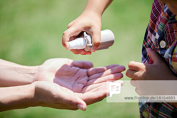Japanisches Kind benutzt Handdesinfektionsmittel in einem Stadtpark