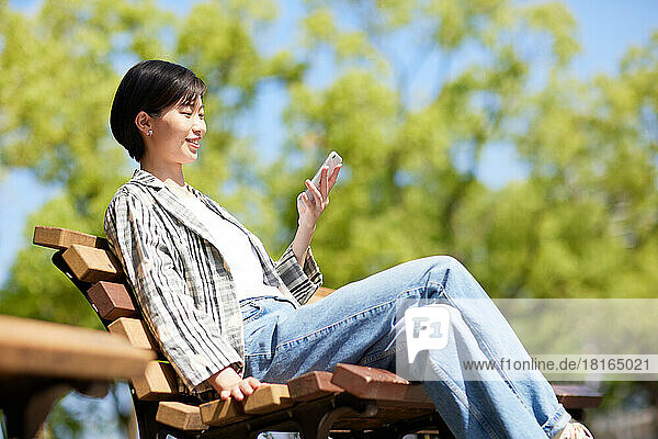 Young Japanese woman using smartphone in a city park
