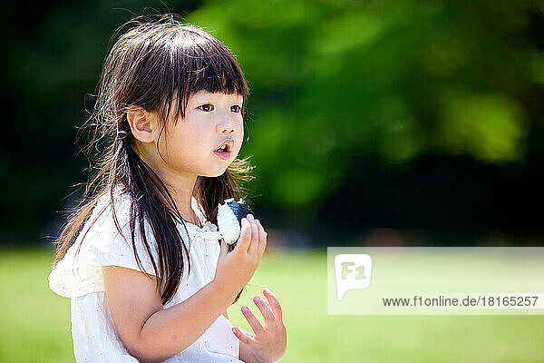 Japanisches Kind beim Essen in einem Stadtpark