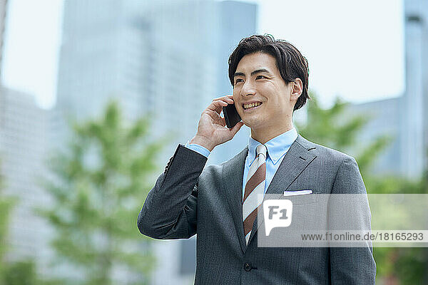 Japanischer Geschäftsmann im Gespräch mit Smartphone
