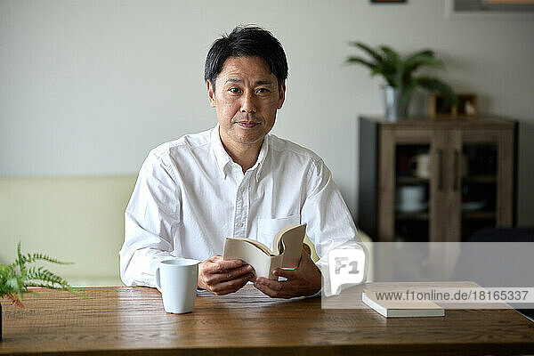 Japanischer Mann mit Buch zu Hause