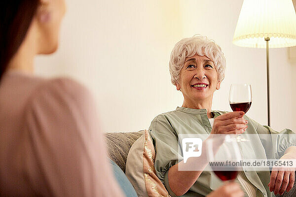 Japanische Senioren und junge Frauen genießen Wein zu Hause