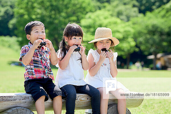 Japanische Kinder beim Essen in einem Stadtpark