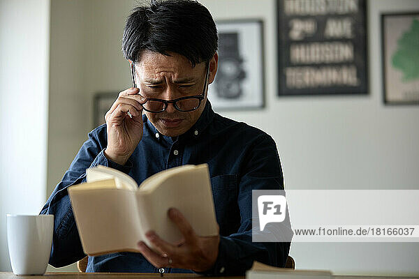 Japanischer Mann mit Alterssichtigkeit liest ein Buch