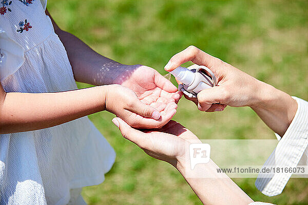 Japanisches Kind benutzt Handdesinfektionsmittel in einem Stadtpark