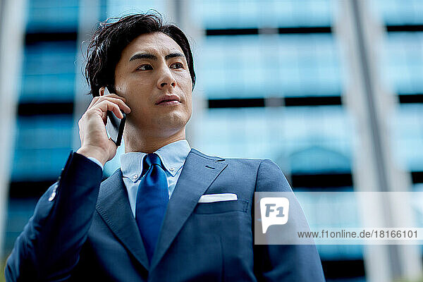 Japanischer Geschäftsmann im Gespräch mit Smartphone