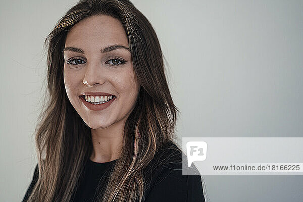 Smiling woman with brown hair against white background